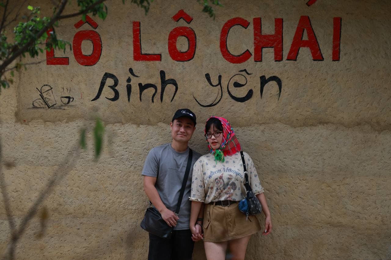 Hai người trước bức tường Lô Lô Chải Bình yên