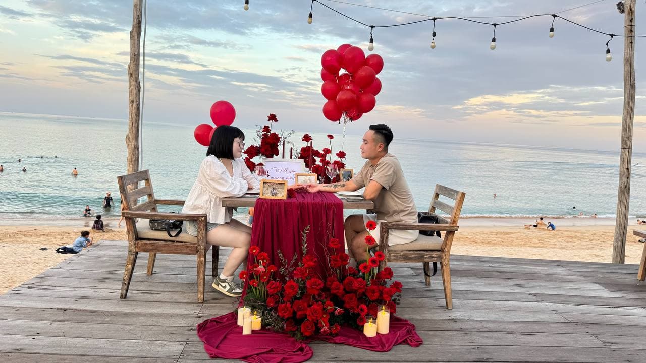 Bàn cầu hôn bên biển với hoa hồng đỏ và bóng bay